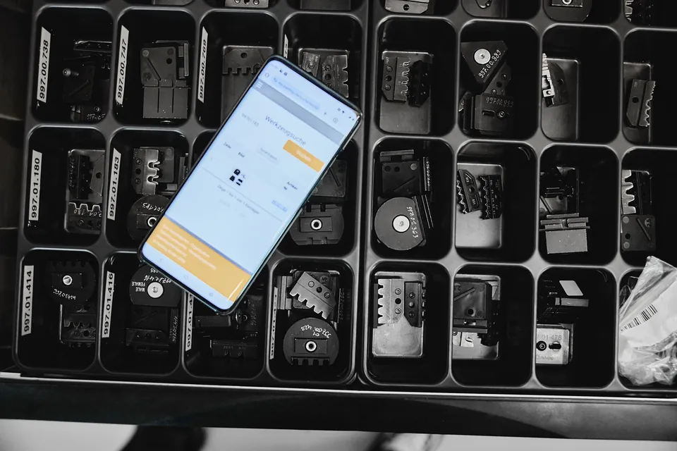 Smartphone auf Crimpwerkzeug-Sortiment mit interner Web-App zur Komponentensuche bei Pahling